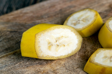not peeled ripe yellow banana cut into pieces on a board