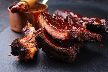 Barbecue pork spare loin ribs St Louis cut with hot honey chili marinade served as close-up on a black board