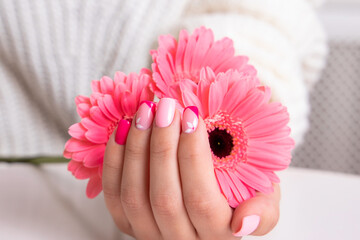 
Beautiful female hands with romantic manicure nails, pink gel polish, gerbera flowers design