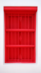 Antique red wooden windows protected by iron bars.