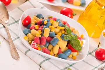 Colored gnocchi with vegetables and sweet corn.