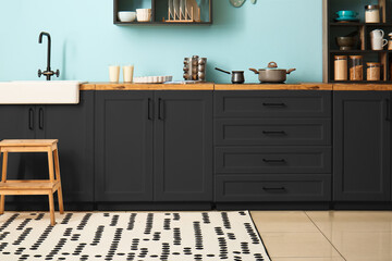 Interior of stylish kitchen with dark furniture and supplies