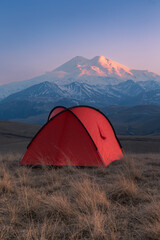 Golden light sunset with bright red tent in front of snow-covered Mount Elbrus, Caucasus, Russia © Igor