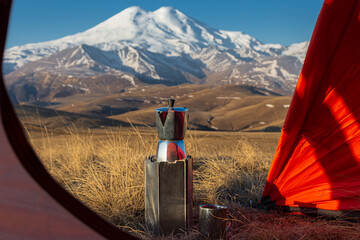 Moka coffee pot at open door of tent against backdrop of snow-capped Mount Elbrus, Caucasus, Russia