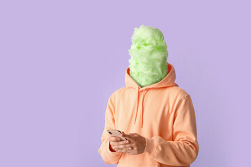 Man with tasty cotton candy instead of his head and phone on lilac background