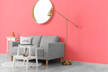 Comfortable sofa and modern lamp near pink wall