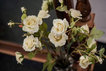 A bouquet of white cream-coloured artificial roses on long stems.