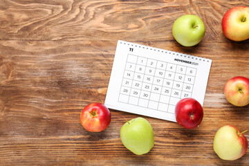 Apples and calendar for November on wooden background. World Vegan Day concept