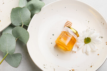 Plate with honey bonbonniere on white background