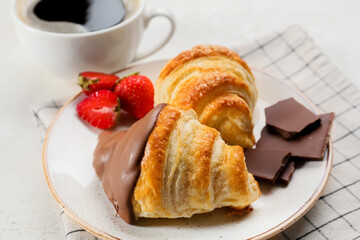 Plate of delicious croissants with strawberry and chocolate on light background