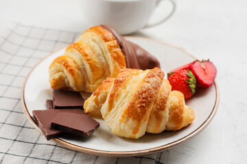 Plate of Delicious croissants with strawberry and chocolate on light background