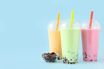 Plastic cups of different tasty bubble tea on blue background