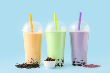 Plastic cups of different tasty bubble tea on blue background