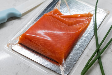 A piece of red fish fillet in a vacuum blister pack. Close-up