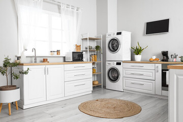 Stylish interior of kitchen with modern washing machines