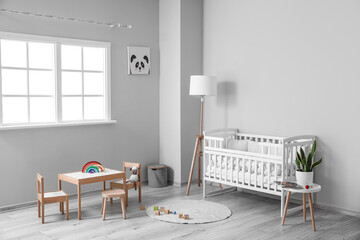 Interior of light nursery with baby crib, lamp and toys