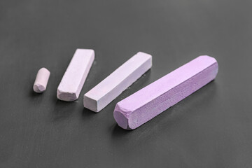Pieces of lilac chalk on blackboard, closeup