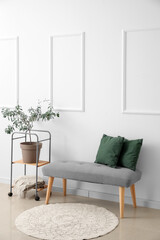 Soft bench with pillows and shelving unit near light wall