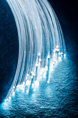 Bundle of optical fibers with lights in the ends. Blue background.