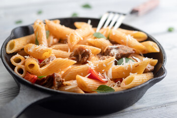 Baked pasta with meat, tomatoes, basil leaves and red pepper