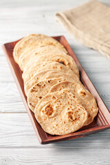 Homemade Indian Traditional Flatbread called Chapati on a white wooden background. Baked indian flatbread. Indian