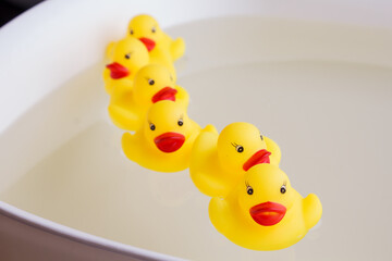 rubber ducks swim one after another in the water.