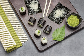Nori sushi, wasabi in a bowl, rice on nori sheet.