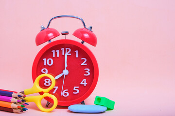 Alarm clock, school supplies and stationery pink background.Preparing child for school.