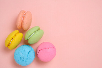 Colorful and bright French macarons cookies on pink background.