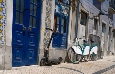Fototapeta na wymiar Typical portugal street in Aveiro old town. House with blue colored doors and renter bikes and scooter