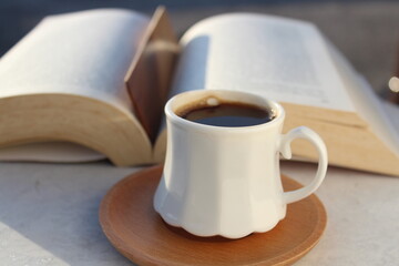 Reading at home balcony under sunset with a cup of Turkish coffee. Wooden bookmark inside the book. Relaxation mood, cultural activity. Freedom, information, knowledge concept. Selective focus. 
