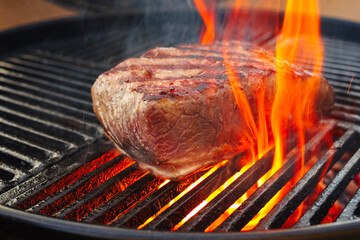 Barbecue dry aged wagyu roast beef steak grilled as close-up on a charcoal grill with fire and smoke