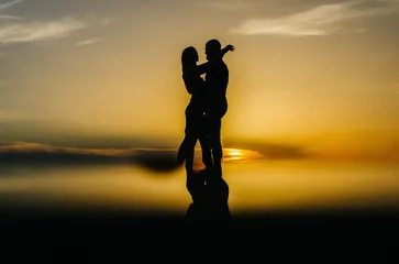 Tuinposter silhouette of a loving couple embracing at sunset © Владимир Паляница