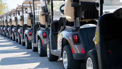 Fototapeta na wymiar A row of electric golf carts on a golf course.