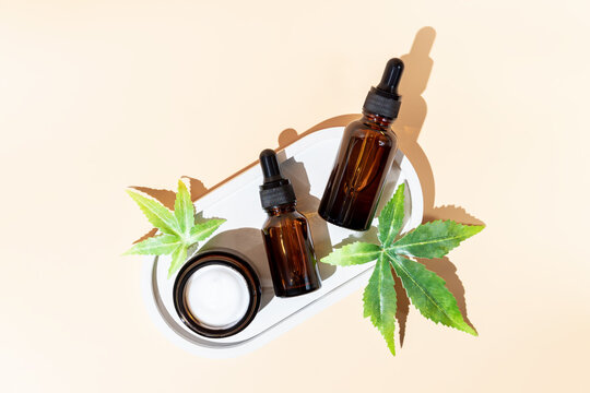 Alternative medicine, natural cosmetics. cbd oil, face cream in open jar and cannabis leaves cosmetics top view , copy space, mock up design