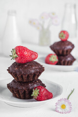 Homemade vegan chocolate muffins with starwberries on a white plate. Gluten free dessert. Healthy breakfast concept.