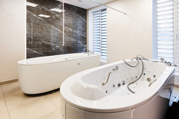 Large hydromassaging bathtub near mirror wall at spa resort