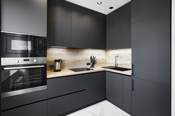 Electrical appliances and black cabinets in empty kitchen