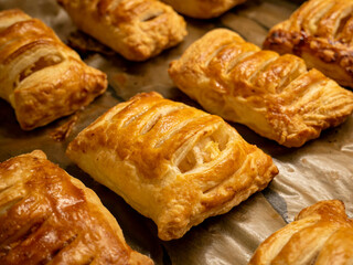 Homemade pastries freshly baked puff pastry puffs with apples on baking paper close-up. Bakery products