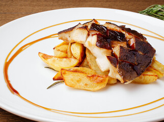 Baked cod, halibut, fillet of white fish. Fish with baked potato slices with lemon and rosemary herbs sauce on a white plate. Serving dishes in the restaurant. Lunch, dinner. Photos for the menu.