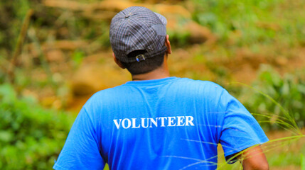 A guy wearing volunteer tshirt during volunteering activity.