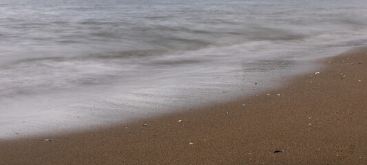 north sea beach with cloudy day with waves on the shore and village in the background of the picture
