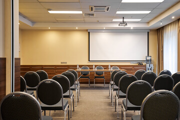 Empty conference hall with chairs and projection screen