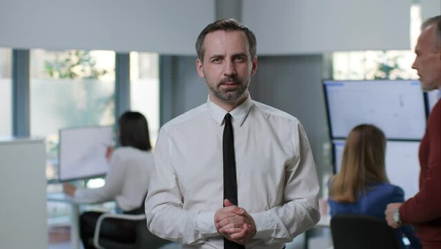 Portrait of mature businessman looking at camera and talking having video conference with colleagues