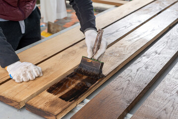 A man holding brush and painting on the wooden table