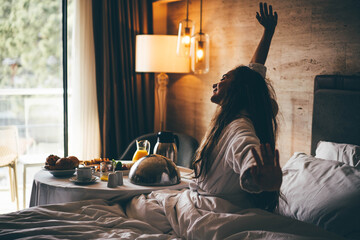 Woman eating breakfast in the hotel room. Room service breakfast in hotel room. - obrazy, fototapety, plakaty