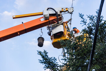 Low angle view of a power line technician at work on an articulated lift, repairing overhead wires in the aftermath of severe storm. With copy space. - obrazy, fototapety, plakaty