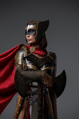 Shot of scandinavian warrior lady dressed in helmet and armor against grey background.
