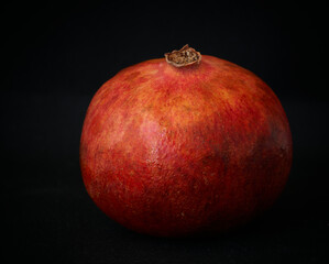 red pomegranate and banana lie on a black background