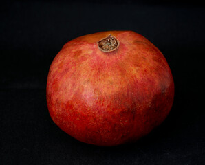red pomegranate and banana lie on a black background